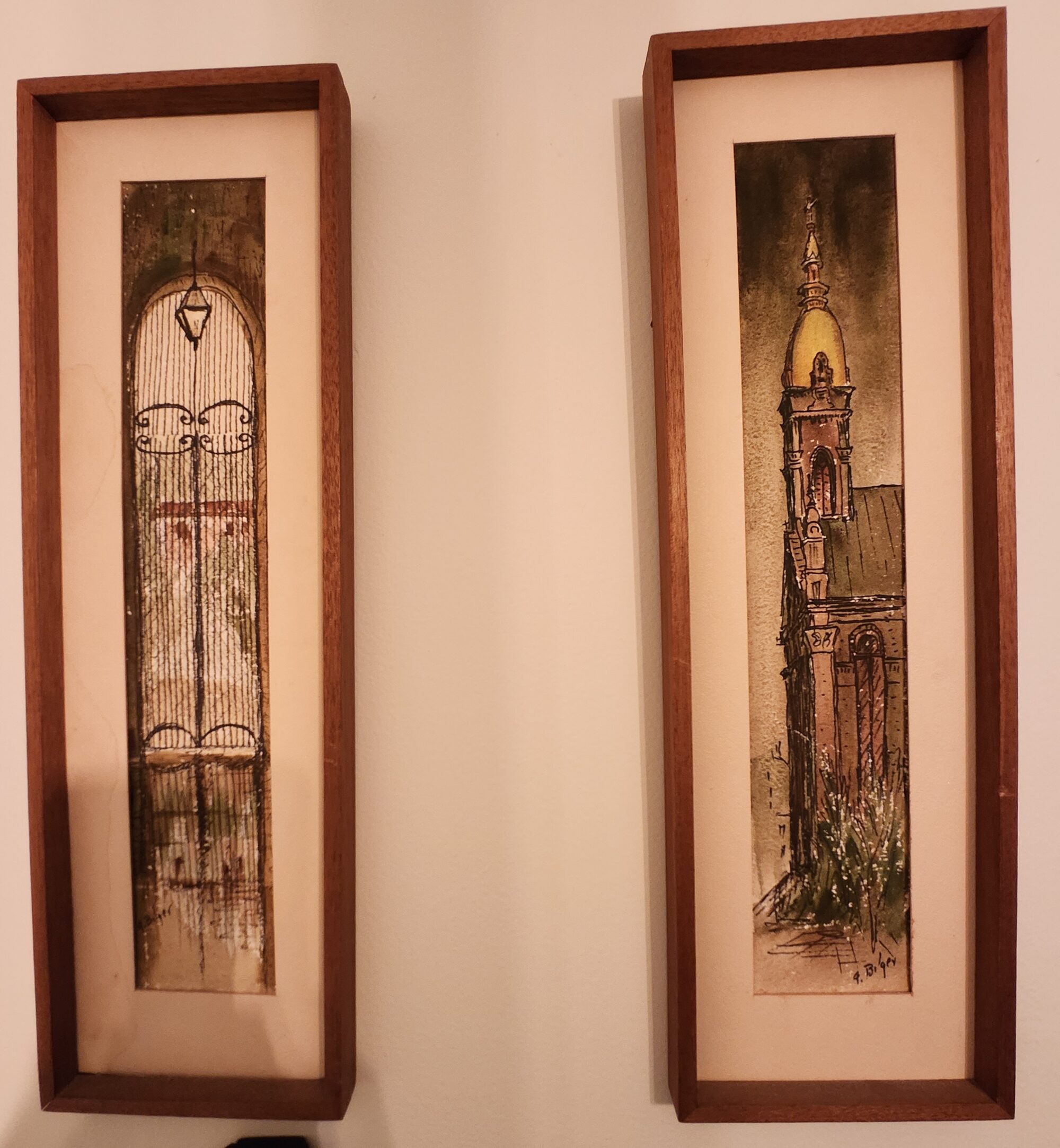 Photo of two long, narrow paintings in wooden frames.