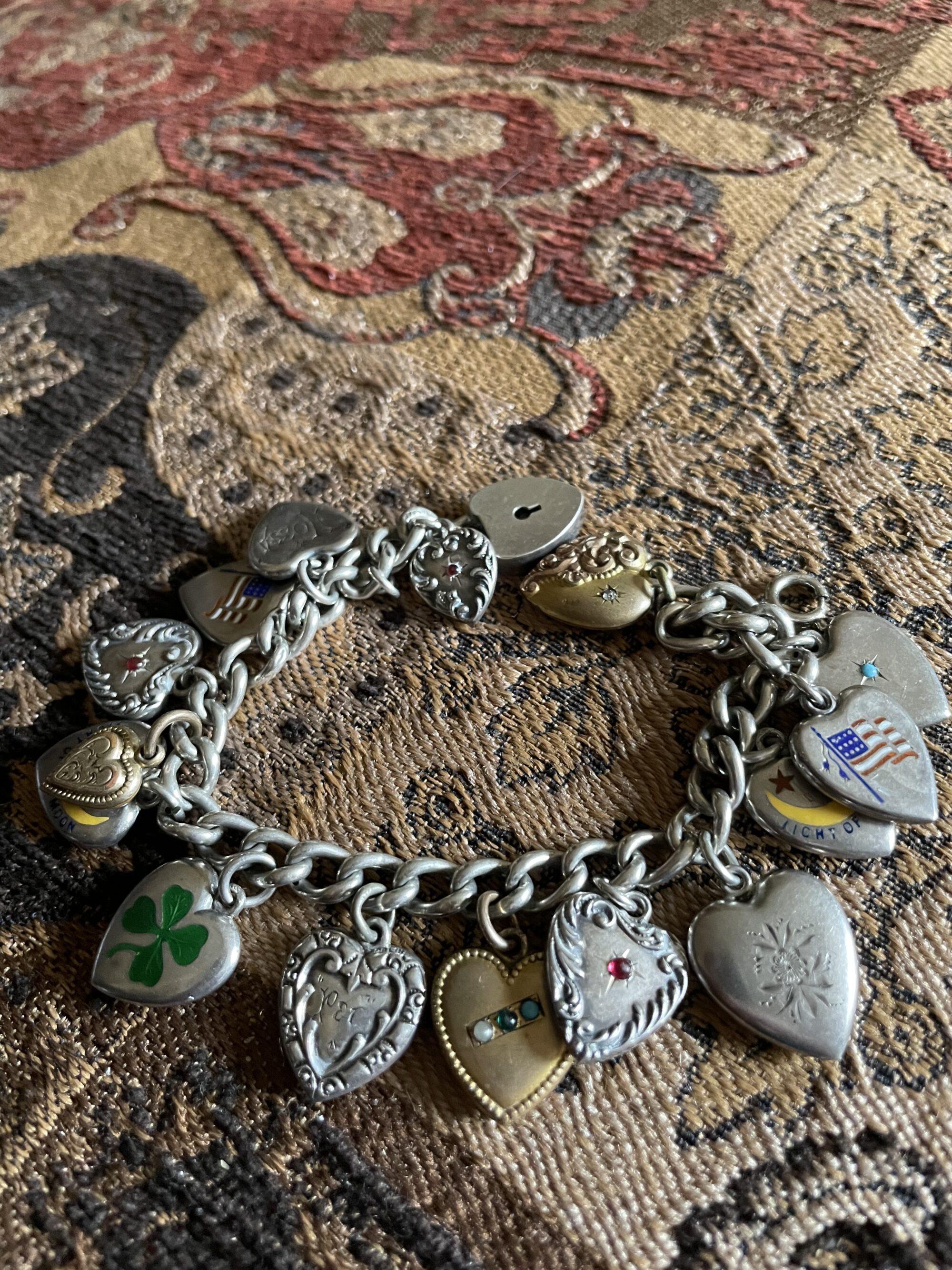 Photo of a silver bracelet with heart charms lying on a rug.