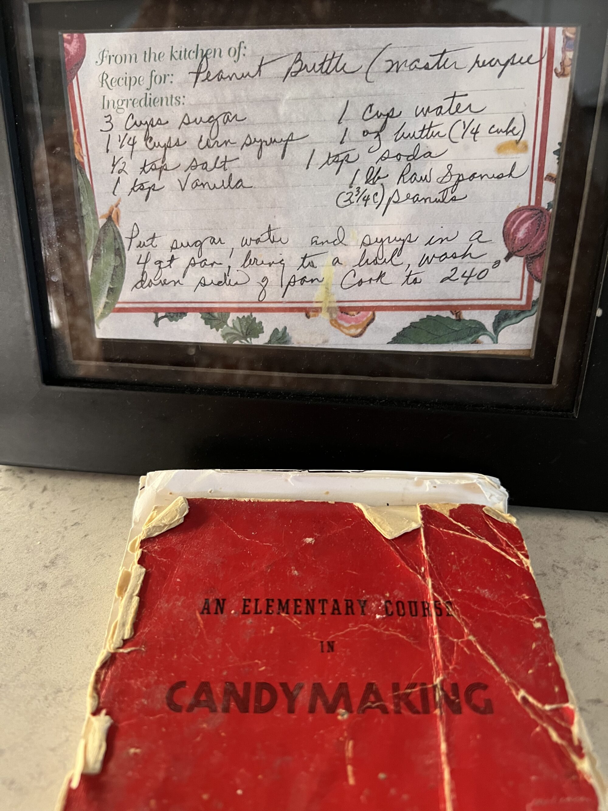 Photo of a worn red candy making book and a framed recipe for peanut brittle.
