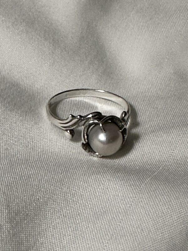 Photo of a silver ring with a pearl setting.