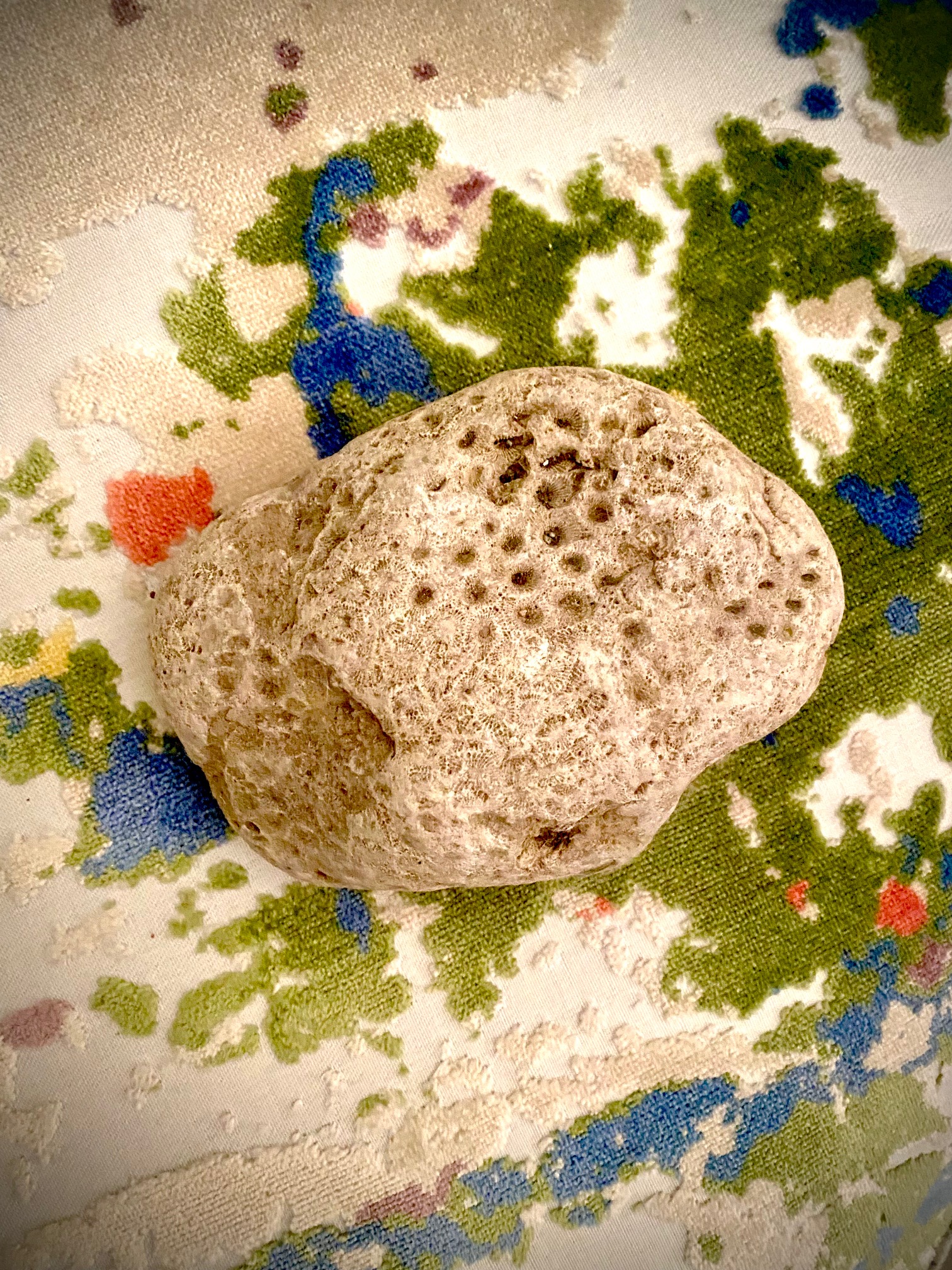 Photo of a large off-white stone on a colorful towel.