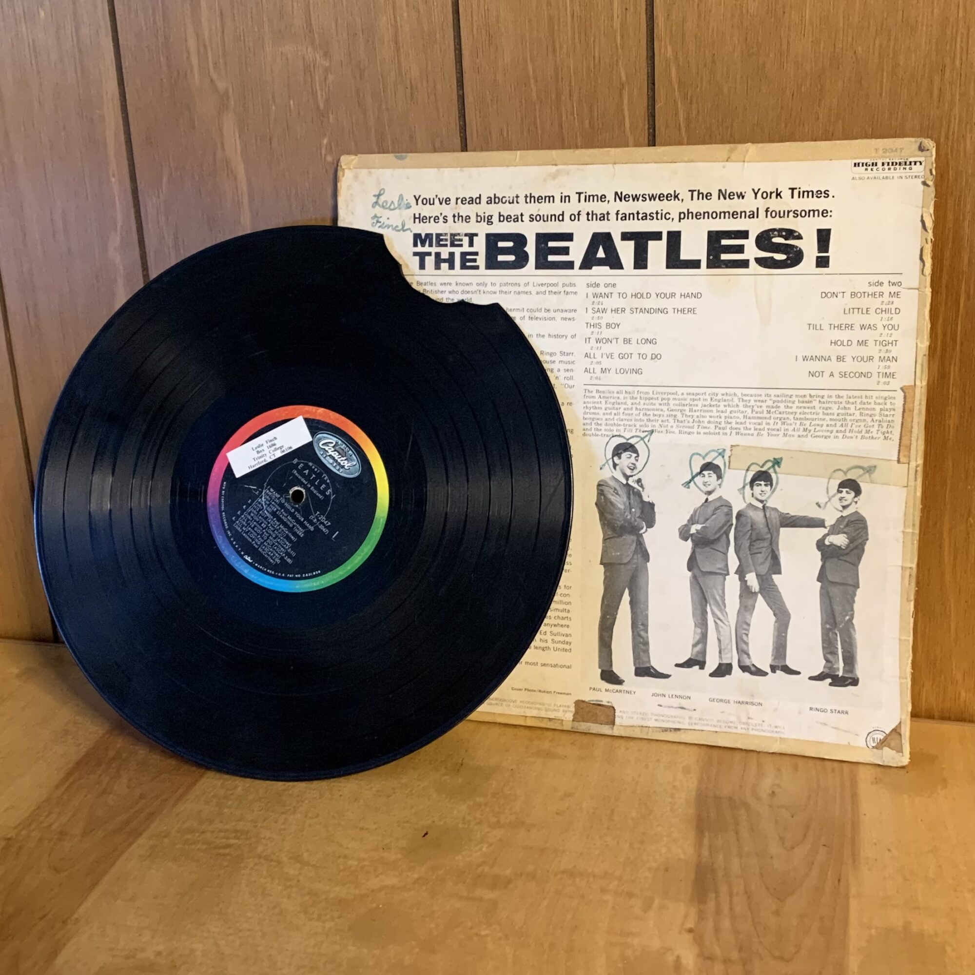 Photo of a chipped vinyl record next to a record sleeve reading Meet The Beatles!