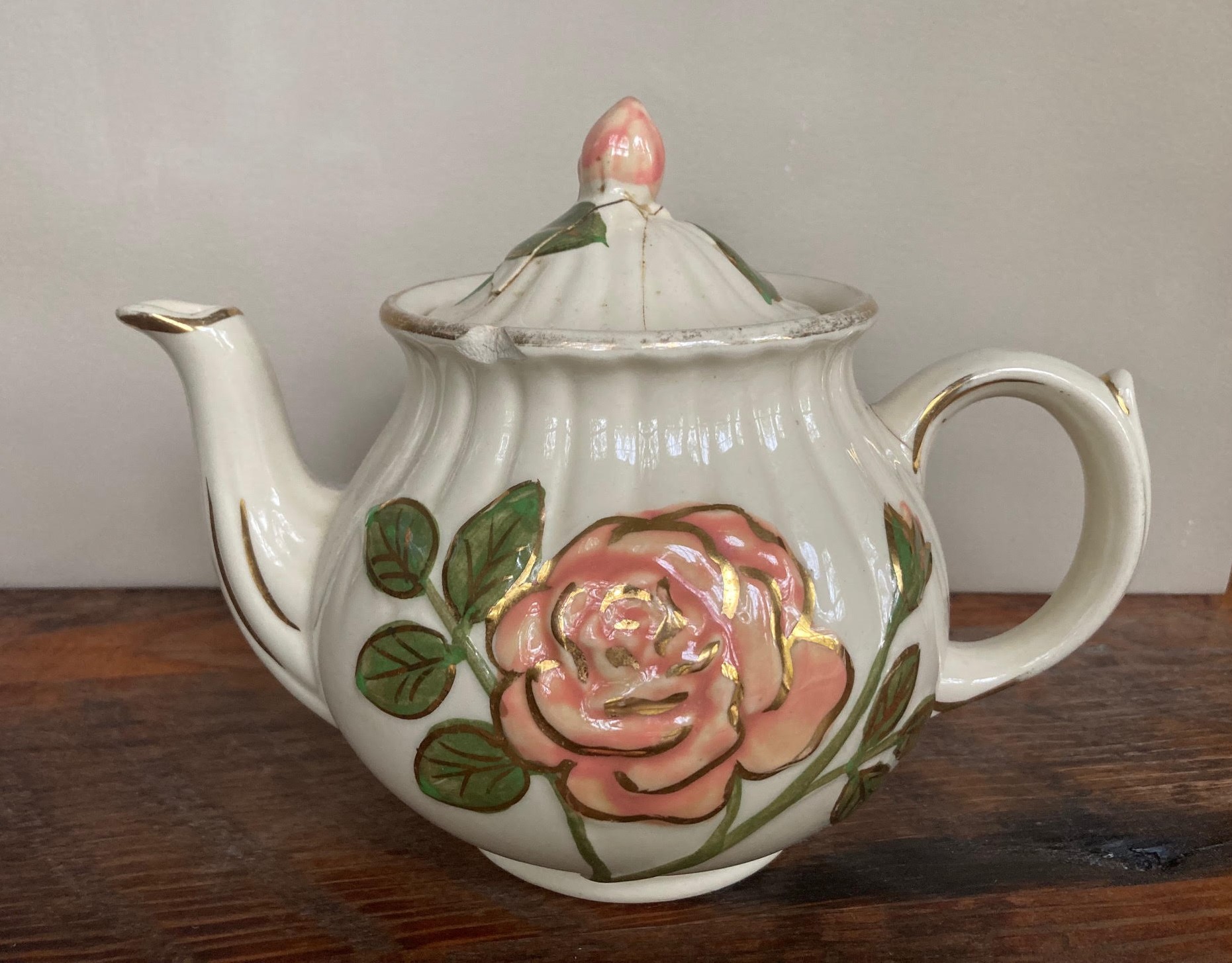 Photo of a porcelain teapot decorated with a pink rose.
