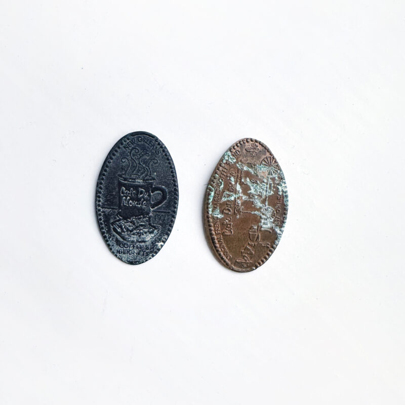 Photo of two flattened pennies printed with the words Cafe Du Monde.