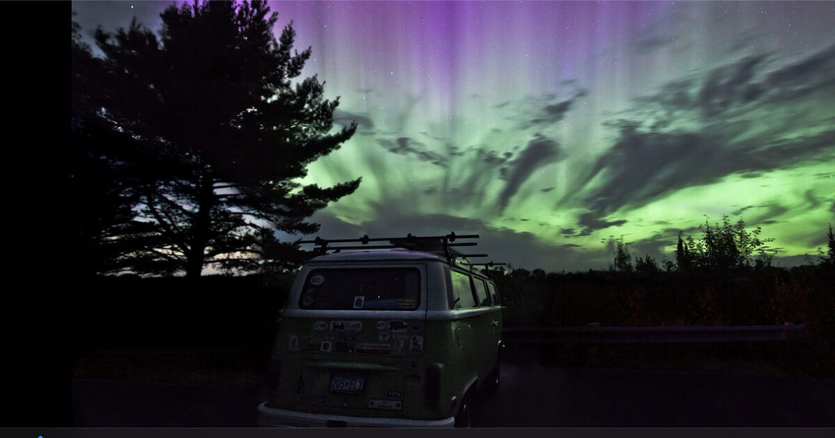 Photo of a parked van at night with during a colorful sunset.
