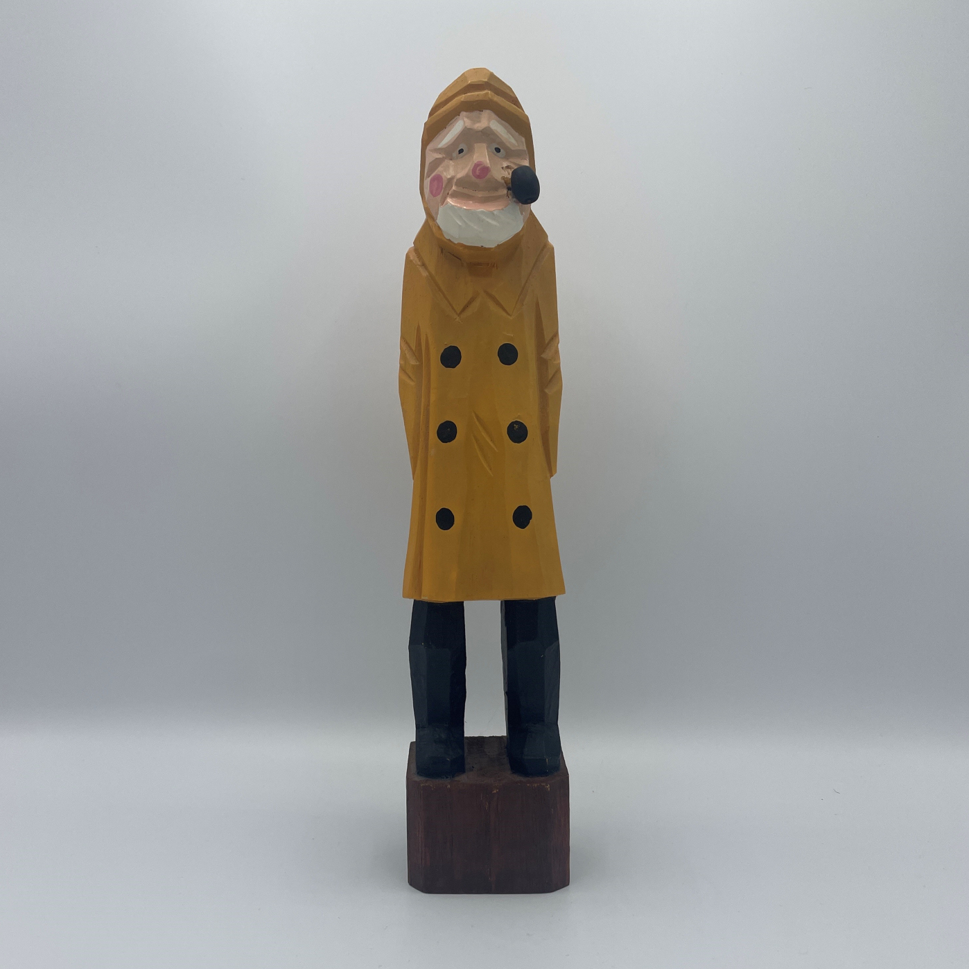 Photo of a small sculpture of a bearded old man wearing a yellow rain jacket and smoking a pipe.