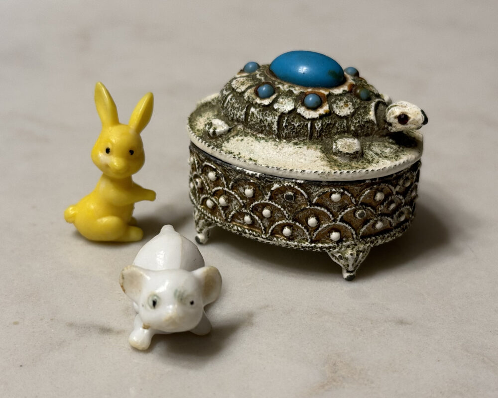 Photo of a small turtle-shaped box sitting next to a small yellow rabbit figurine and a small white mouse figurine.