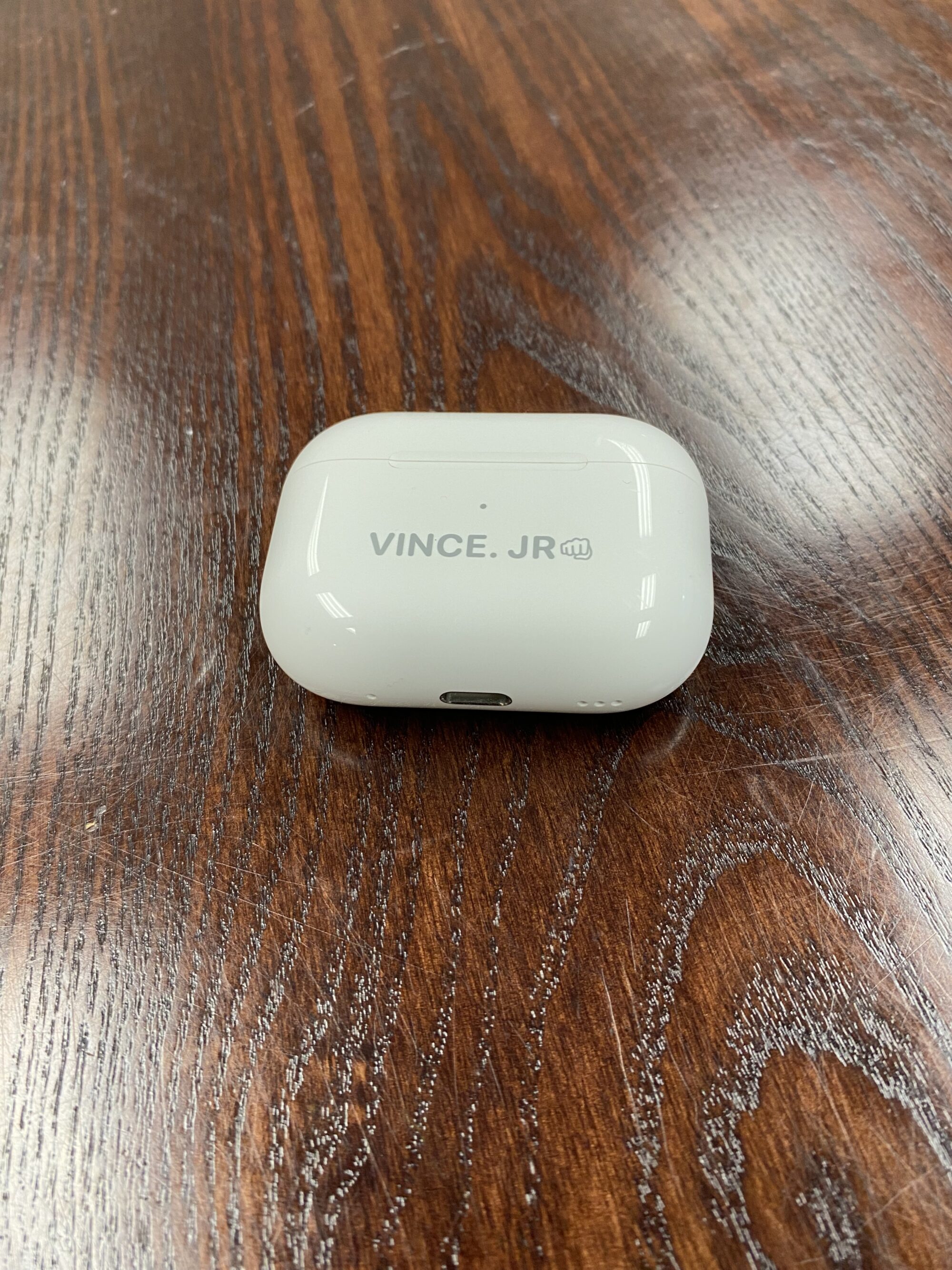 Photo of a white AirPods case on wooden tabletop surface.