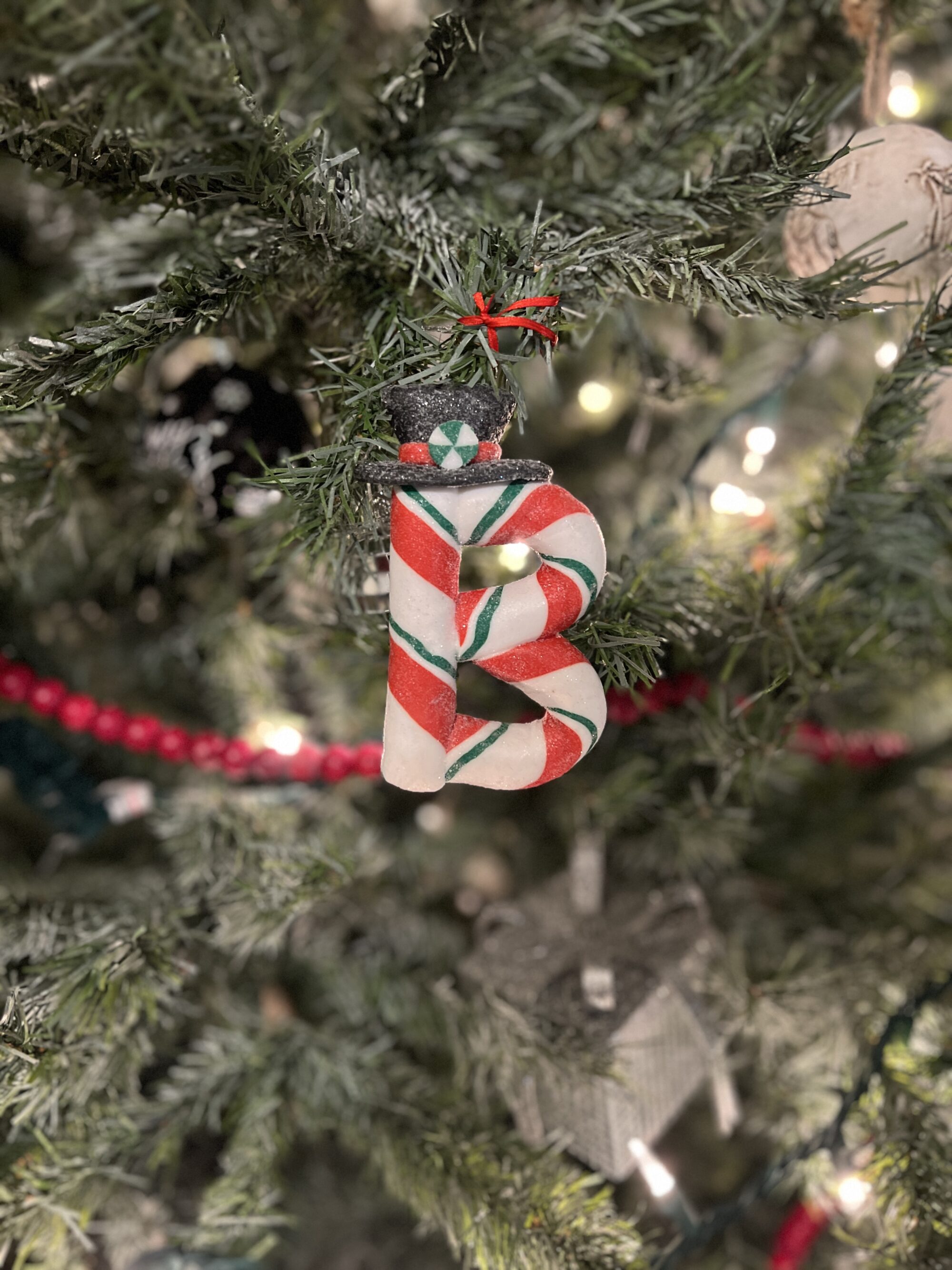 Photo of an ornament shaped like the letter B hanging on a Christmas tree.