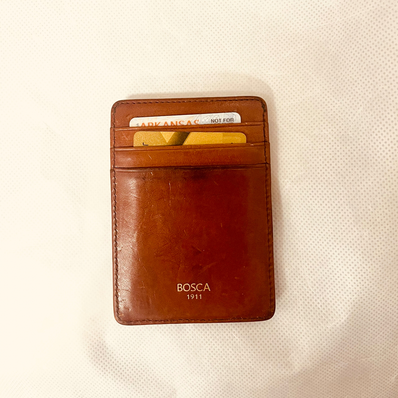 Photo of a small brown Bosca wallet with a few credit cards in the slots.
