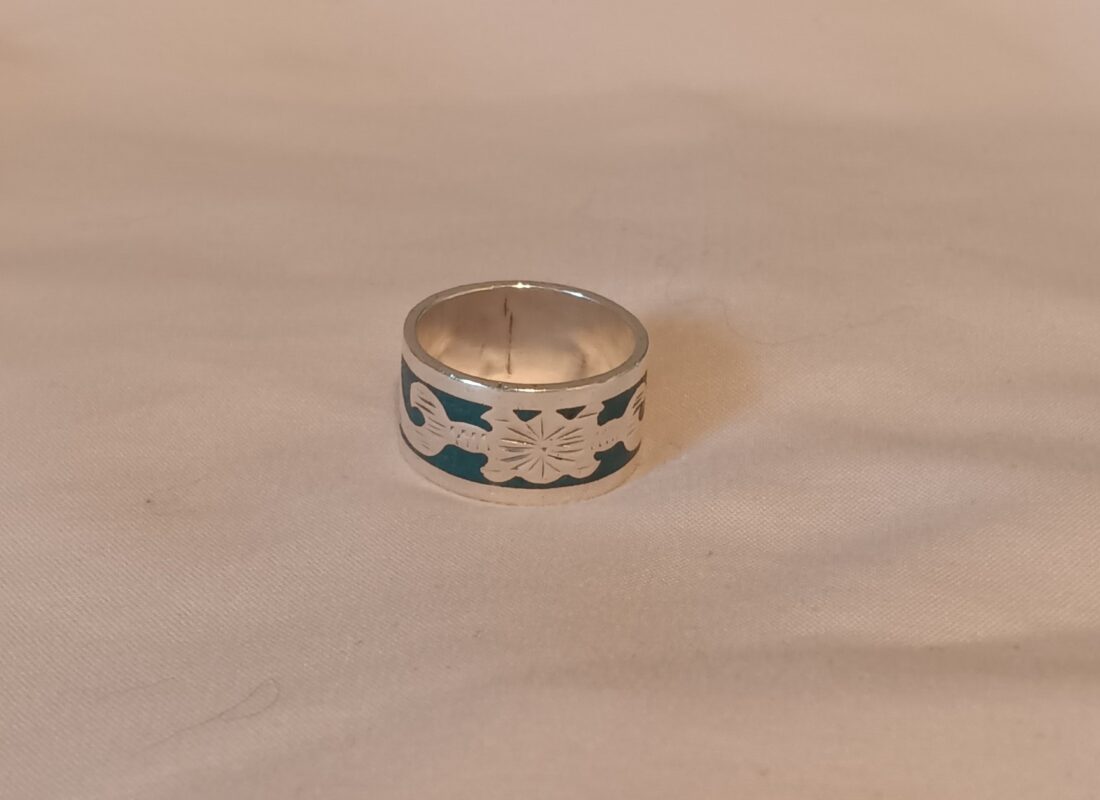 Photo of a thick silver banded ring with an abstract inlay pattern.