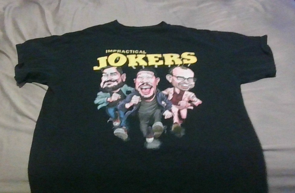 Photo of a black t-shirt with three men and the words Impractical Jokers on the front.