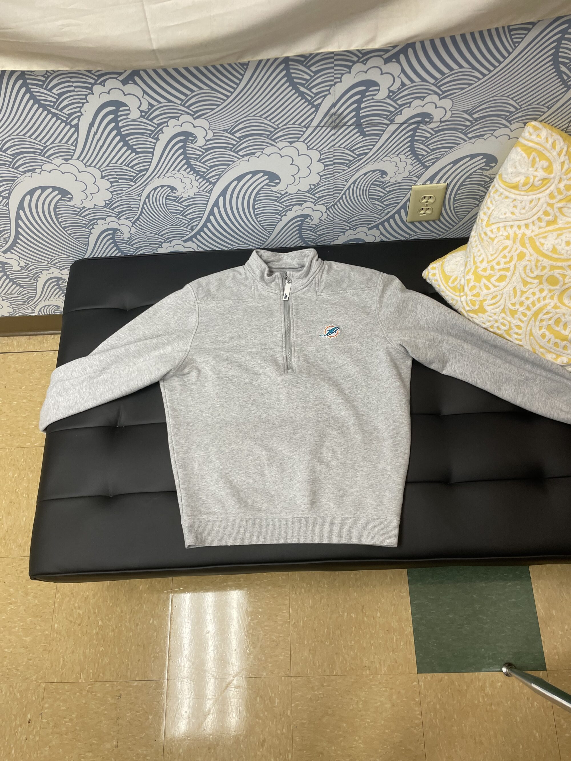 Photo of a gray sweater with a small Miami Dolphins logo on the chest.