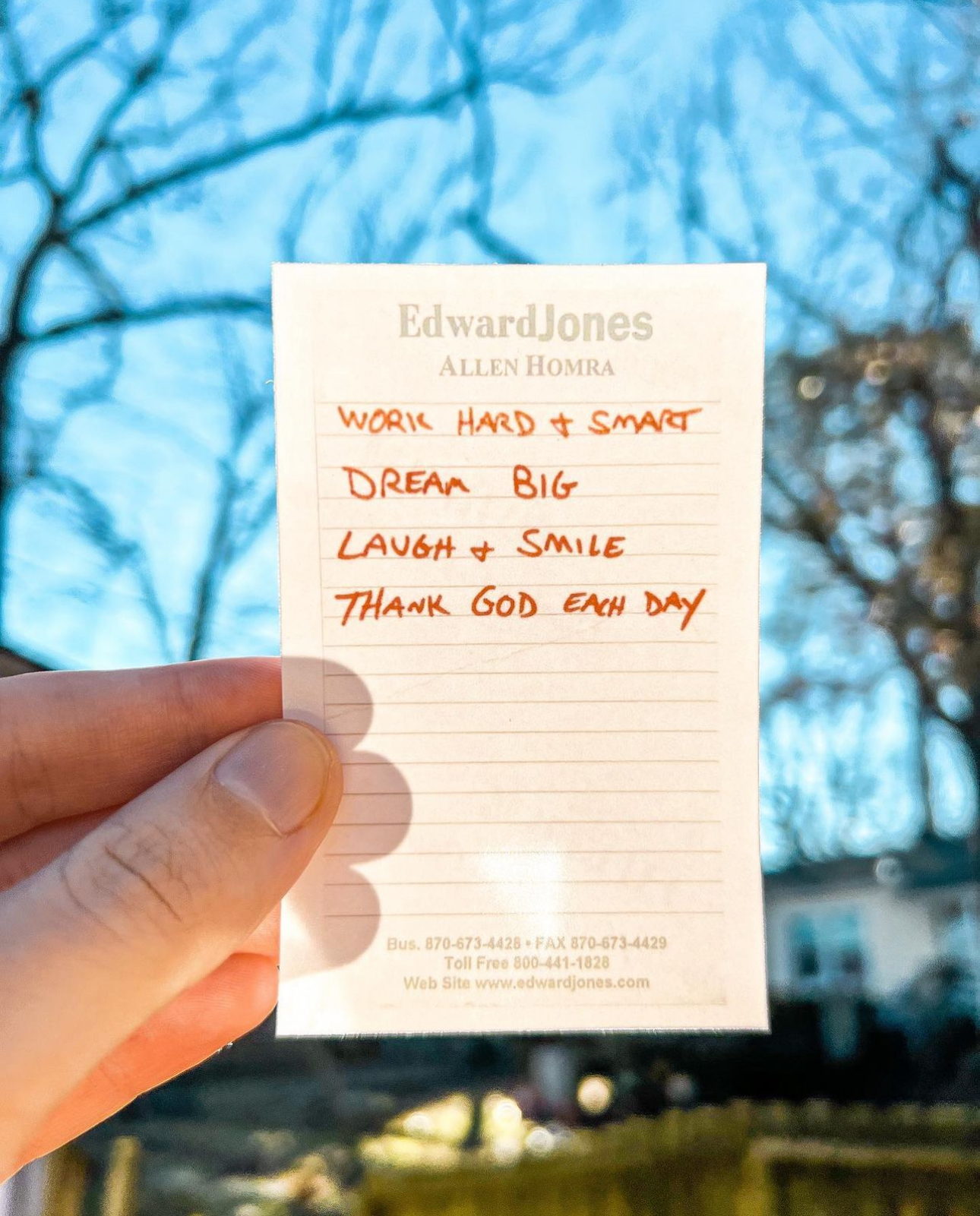 Photo of a hand holding a handwritten list on an sheet of Edward Jones notepad paper.