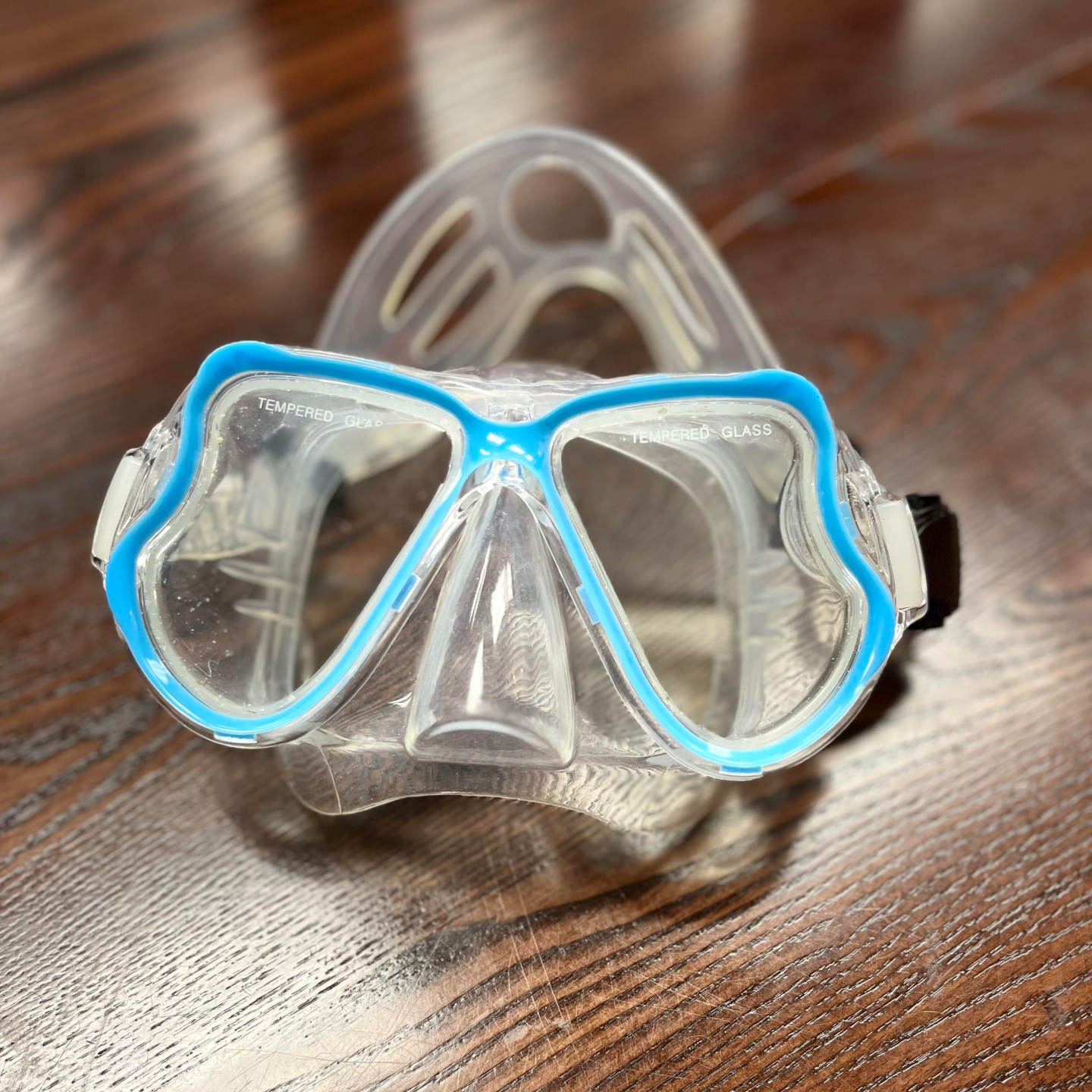 Photo of blue snorkeling googles on a wooden tabletop surface.